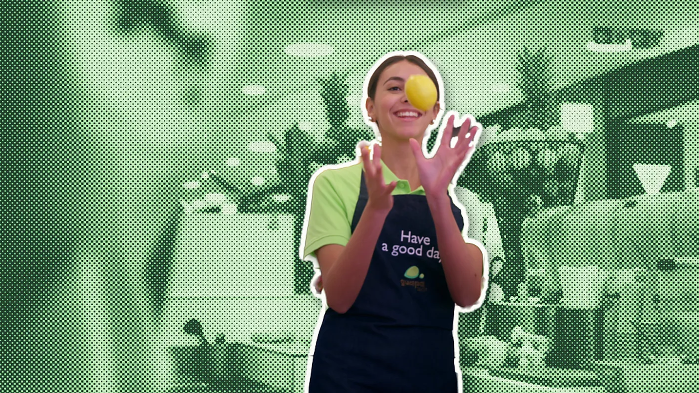 Une employée de Guapa Juice jongle avec un citron, découpée en couleurs sur le bar à jus en trame de points verte
