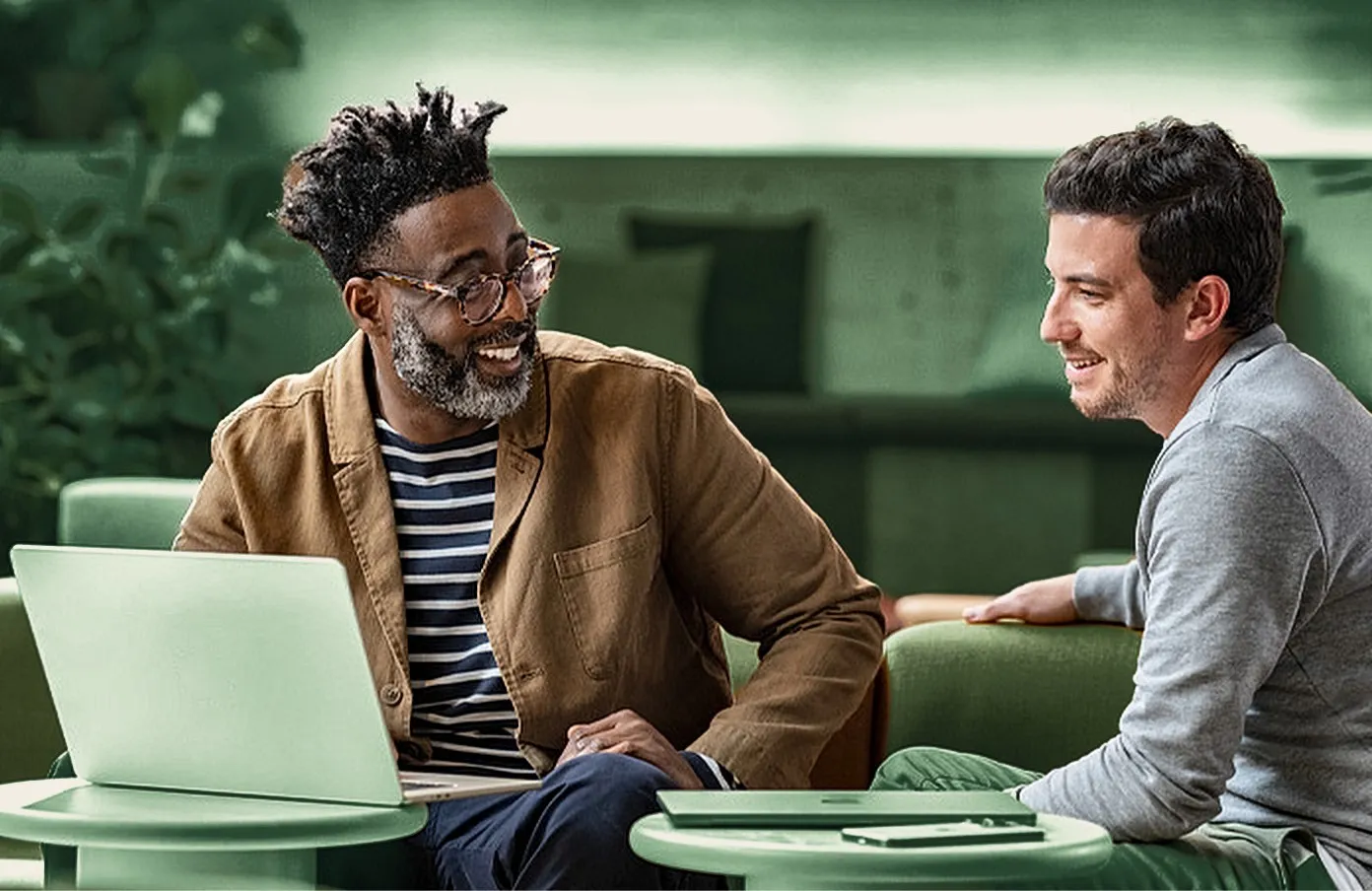 Deux collègues souriants devant un ordinateur portable.
