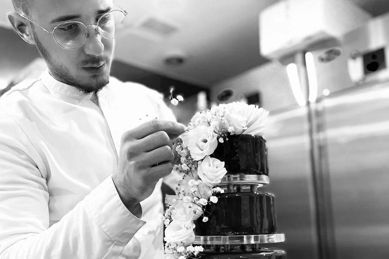 Ayoub Bouricha, propriétaire de Dayou Paris, décore de roses blanches un gâteau à étages.