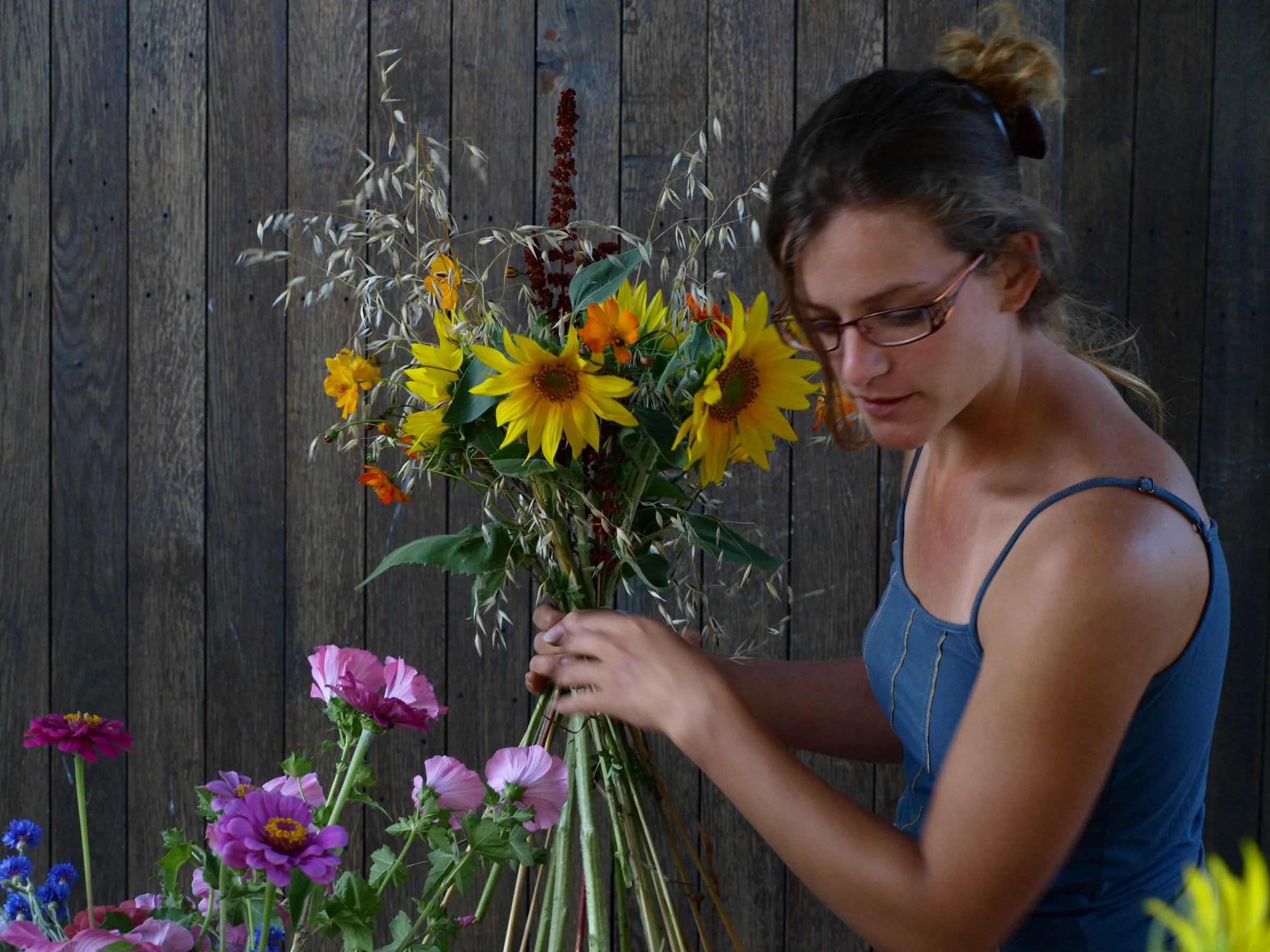 Fleuriste qui compose un bouquet de tournesols et de fleurs des champs